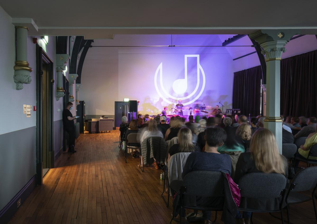 Image of a live music event in a community hall.