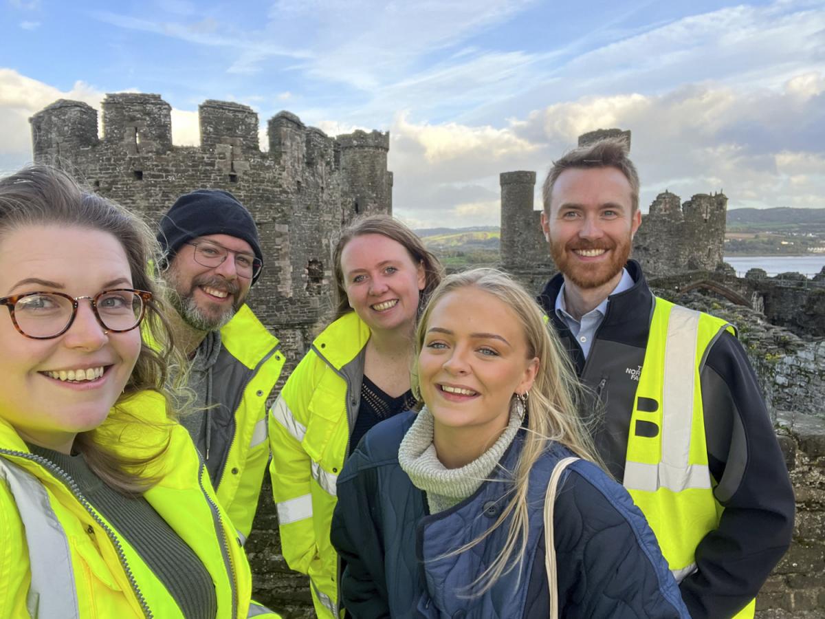 A group of people smiling at World Heritage Site, Caernarfon Castle.