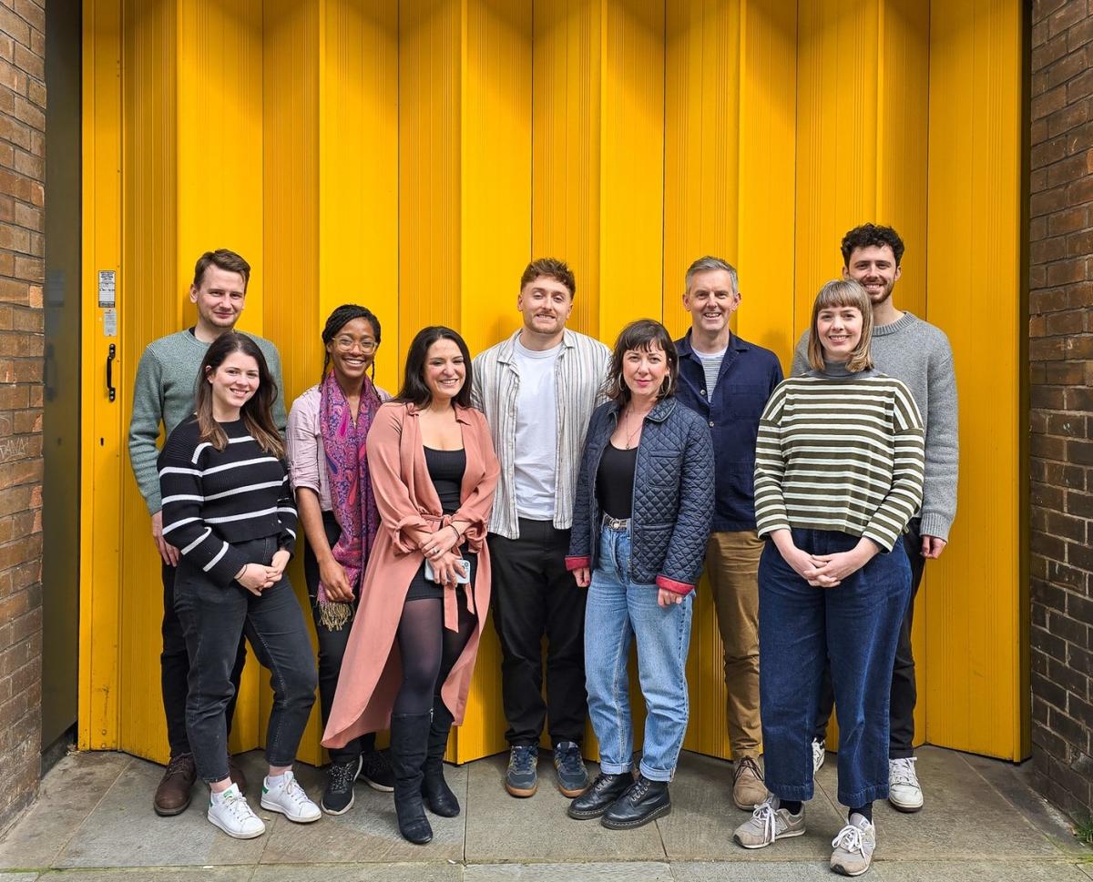 Group of people stood in front of a yellow background