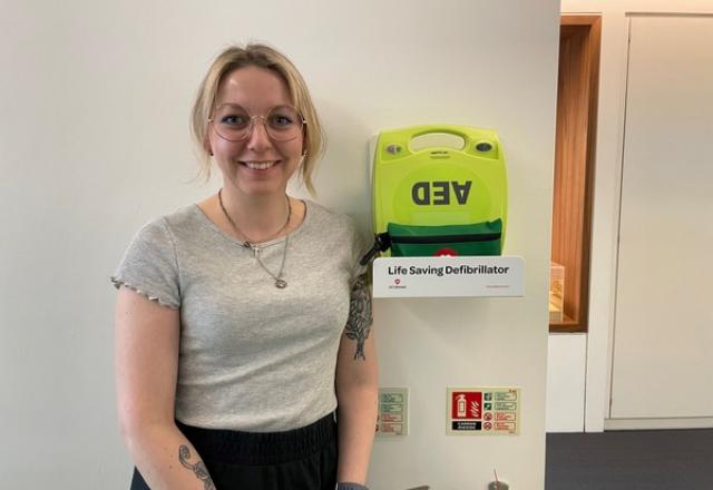 gracy avery standing to the left of installed defibrillator in office