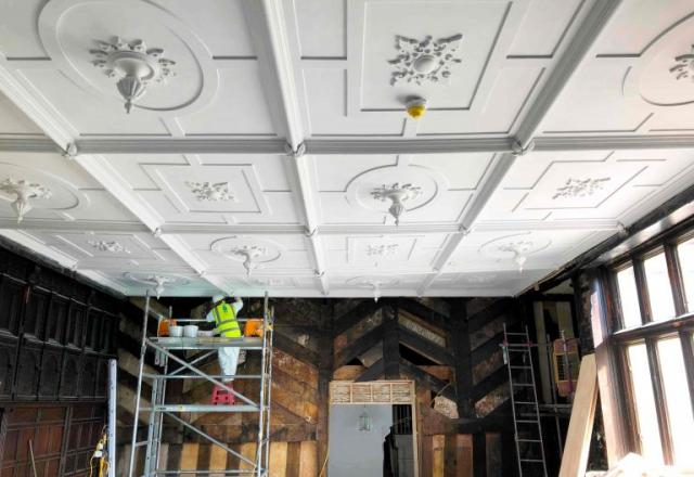 worker in hi-vis working on historic ceiling