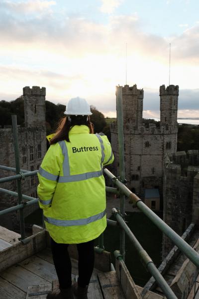 A lady in high vis views Caernarfon Castle from the castle walls