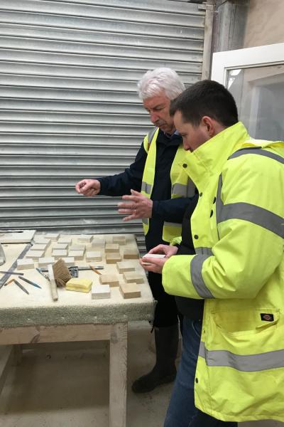 two men (one in a hi vis jacket) consider stone samples