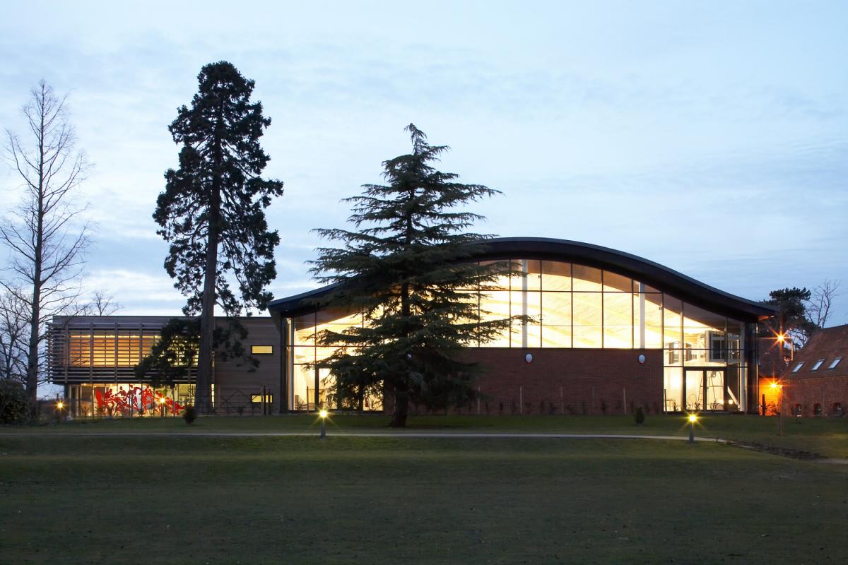 Exterior image of a contemporary sports centre with curved roof.