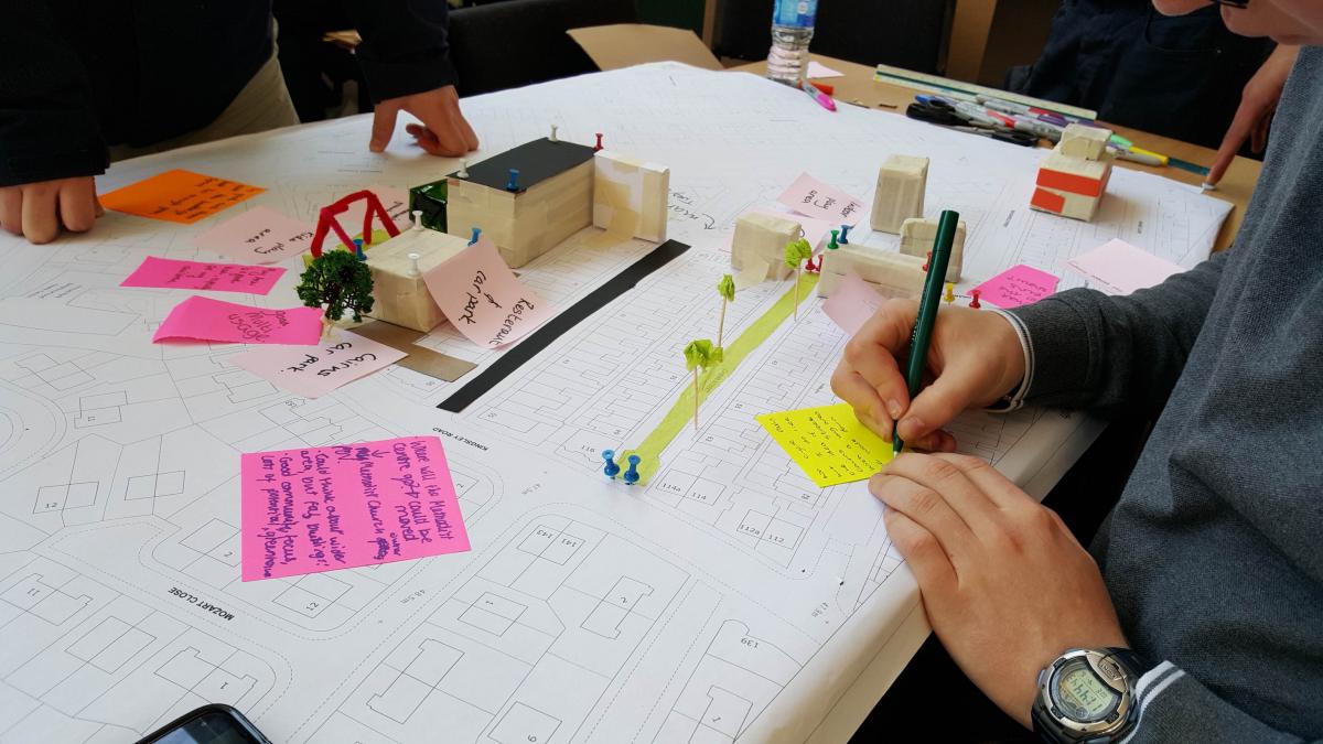 over shoulder shot of people writing on sticky notes on table at workshop