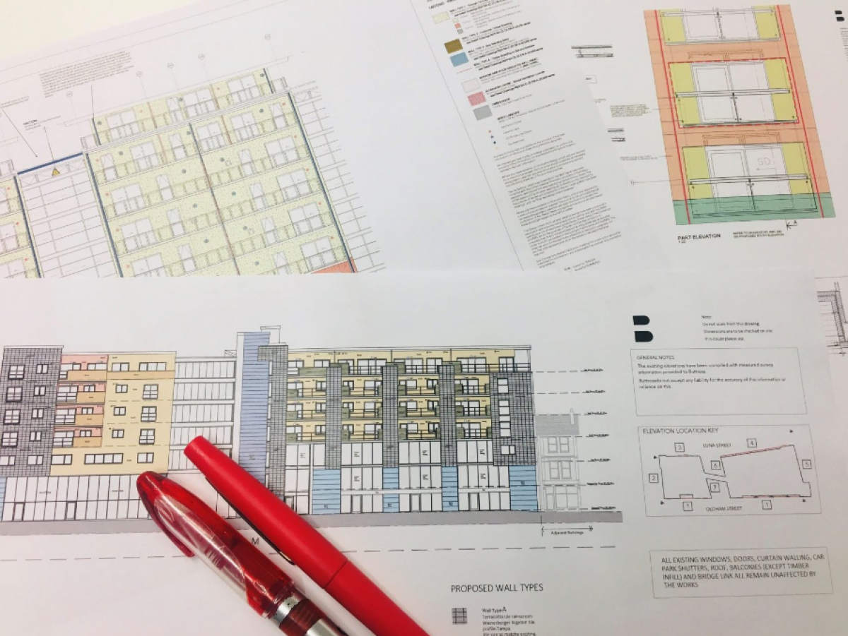 above view of blueprint drawings on table with red pens