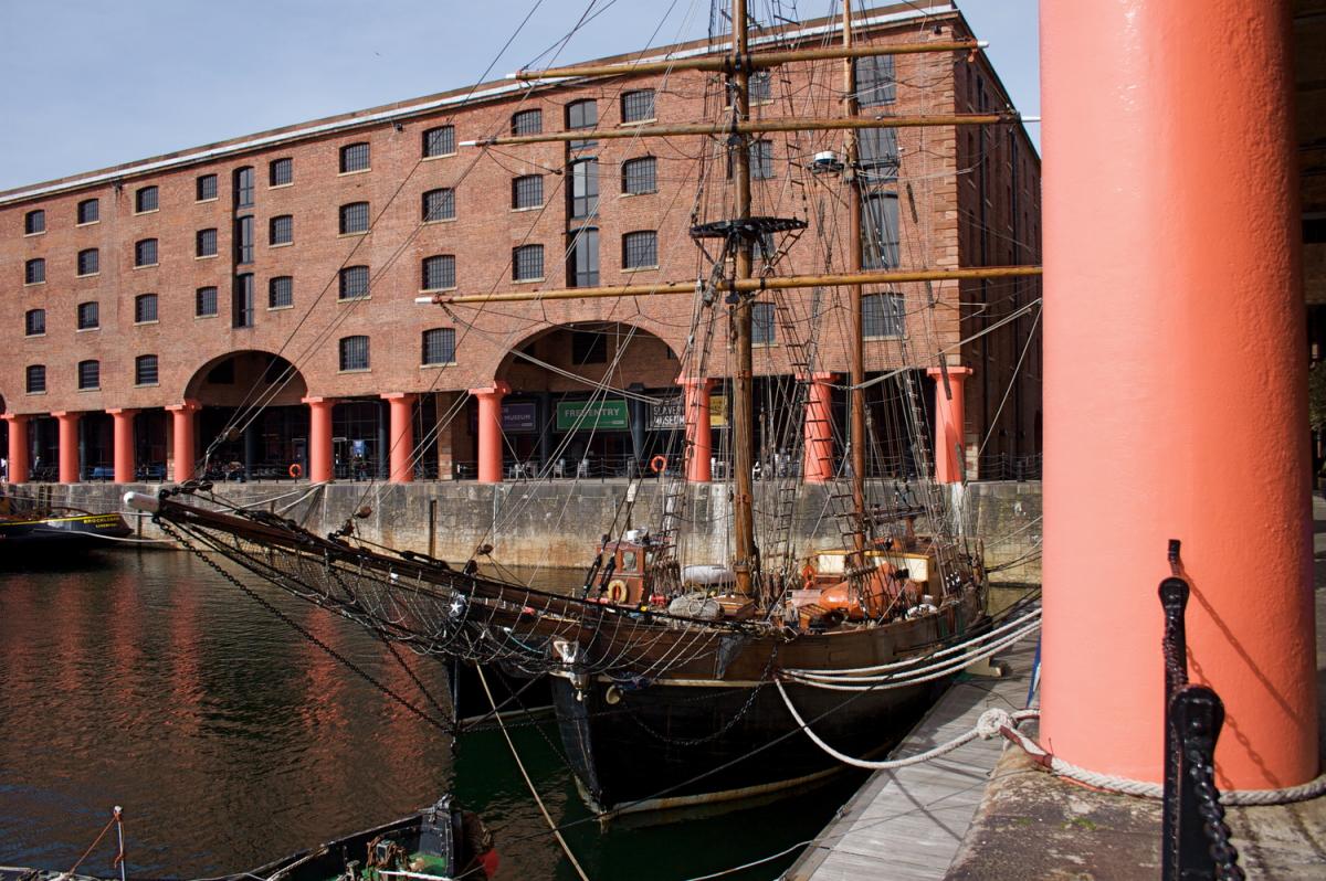 albert dock tall ship docked up with large brick building with red columns in the background