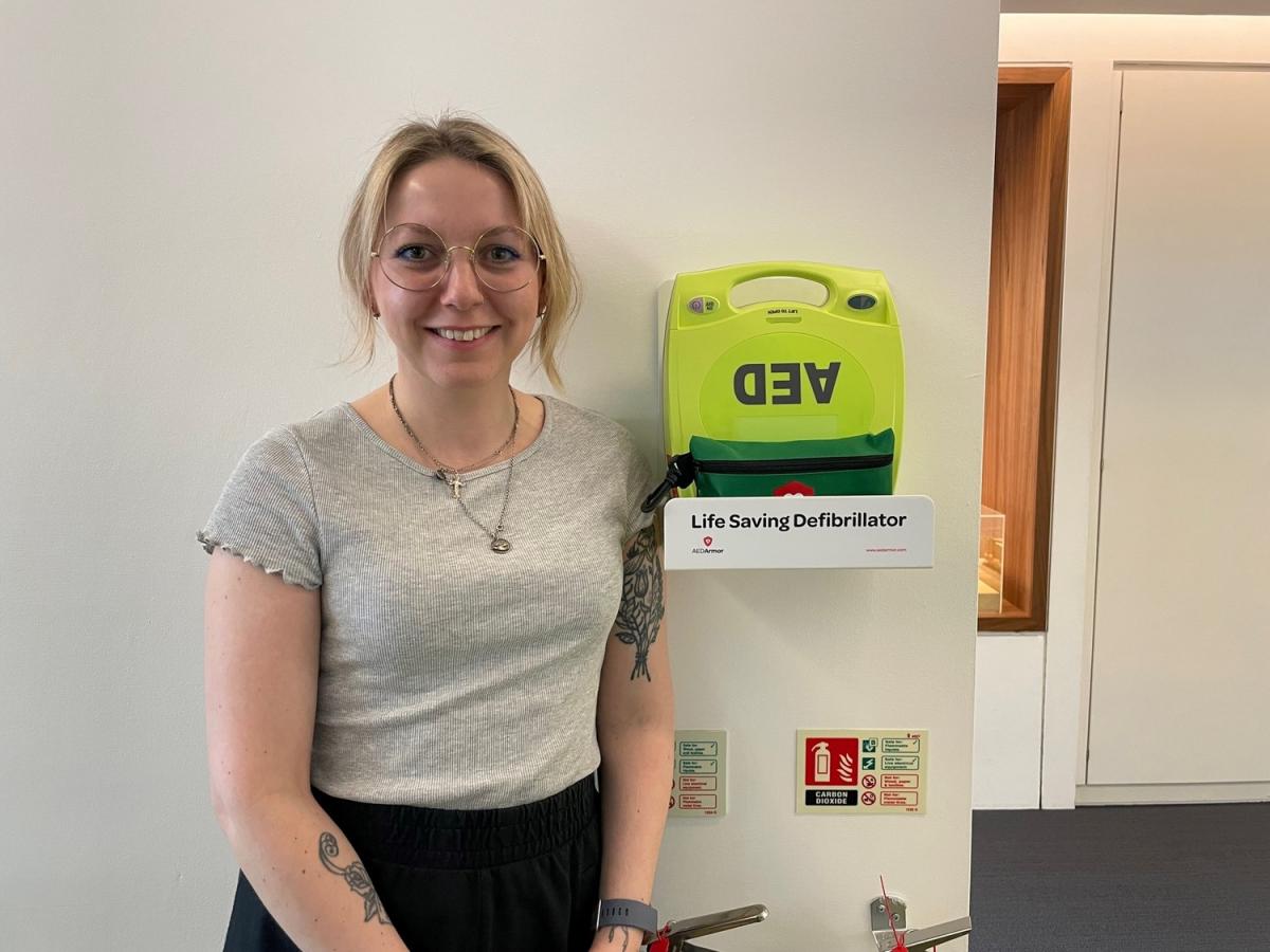 gracy avery standing to the left of installed defibrillator in office