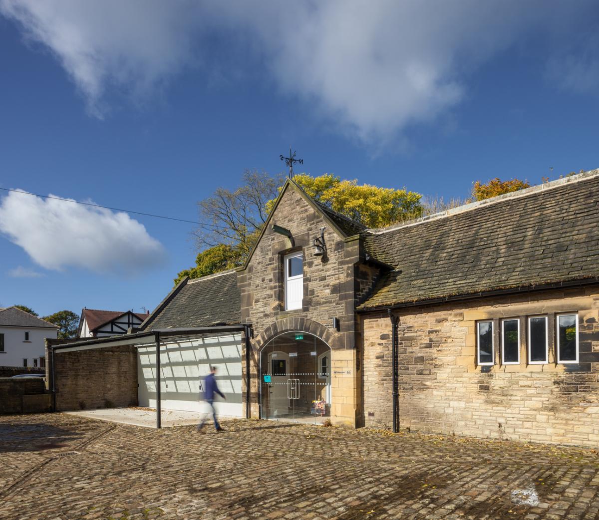 exterior of haworth art studio, barn type building with tall glass door, man entering building