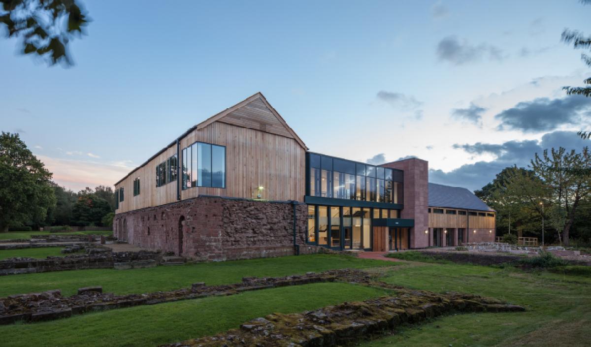 exterior of norton priory, large glass windowed foyer and wooden structure building on top of monastery