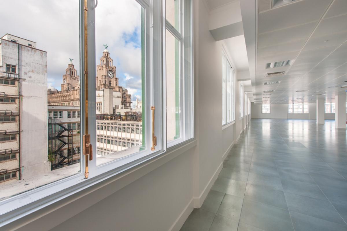 Image of an open-place office space. A view of Liverpool's Royal Liver Building can be seen through the window.