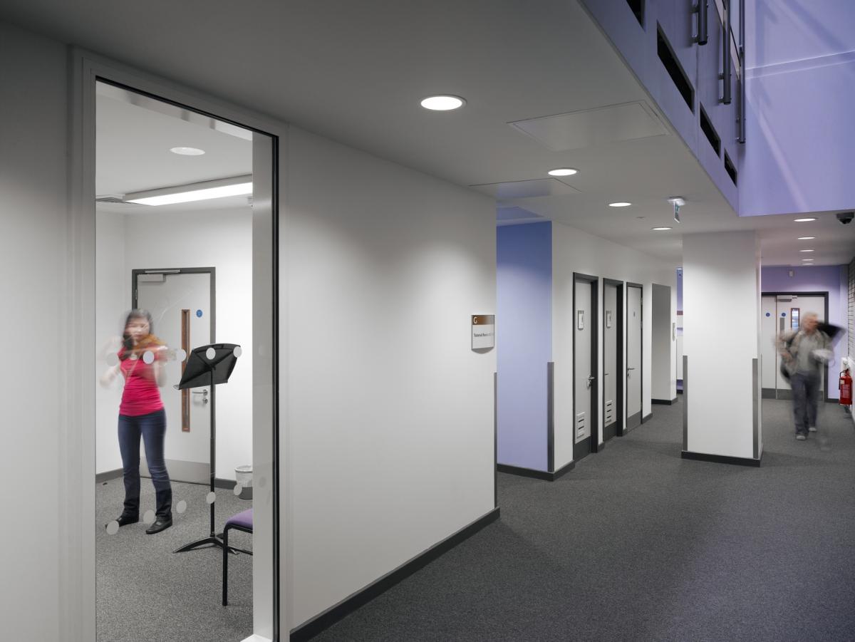 Image of a music rehearsal room. A person can be seen playing an instrument through the window.