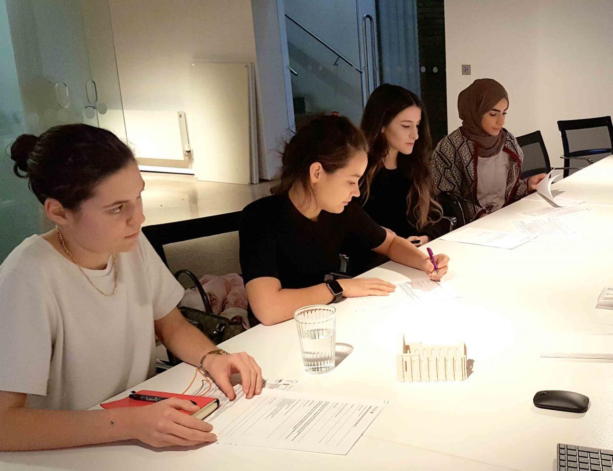 students sat at table in studio with worksheets