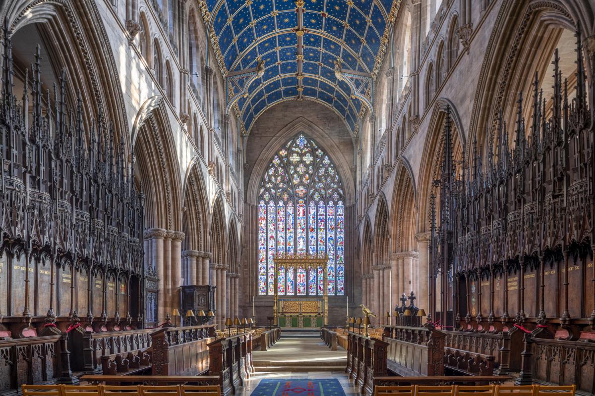 interior of cathedral with rows of pews, high intricately decorated ceiling