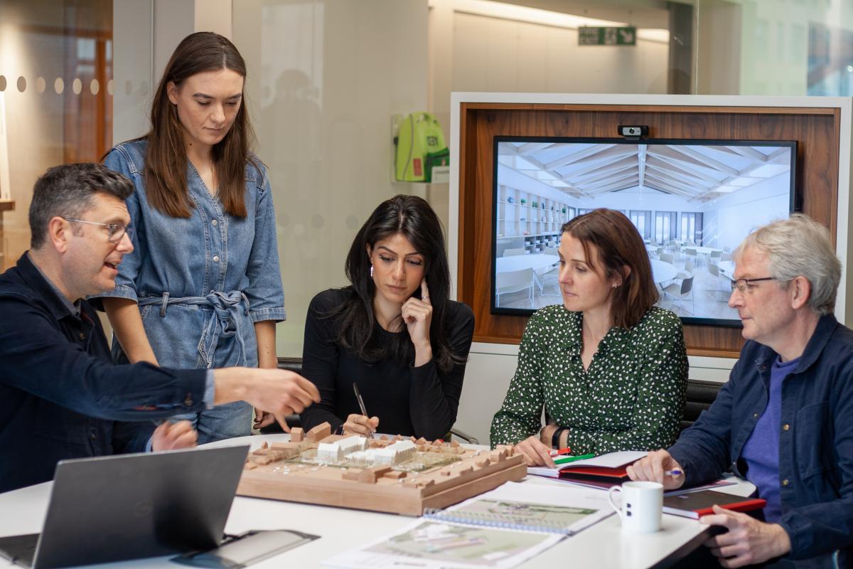 Group of architects examining a model.