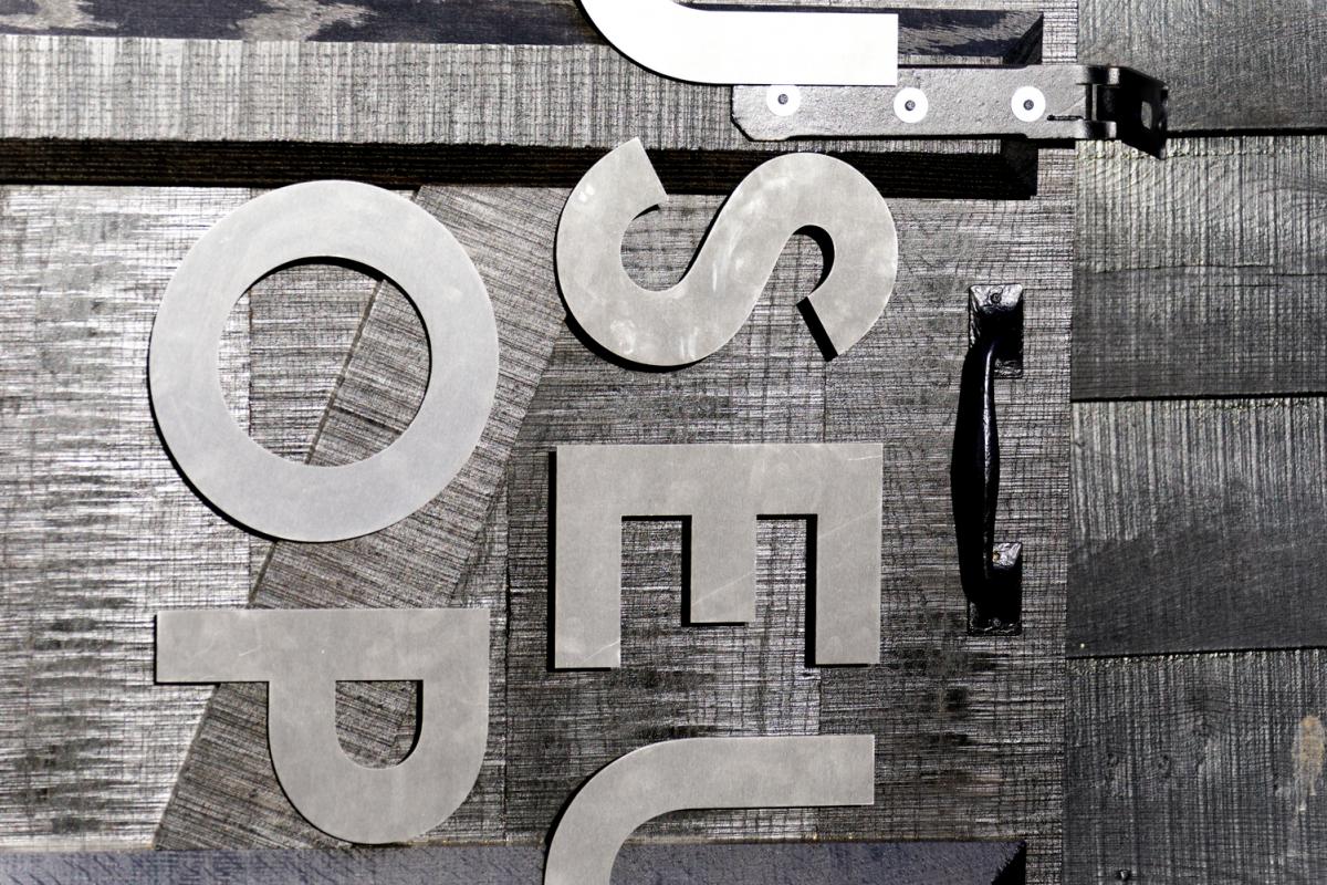 a close up of the word museum shop in black letters on a black wooden door