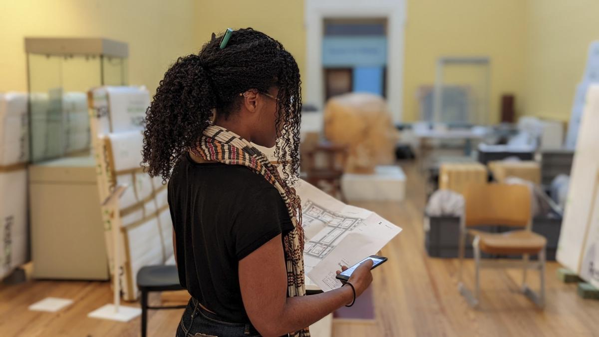 a lady looks at plans whilst in a museum gallery
