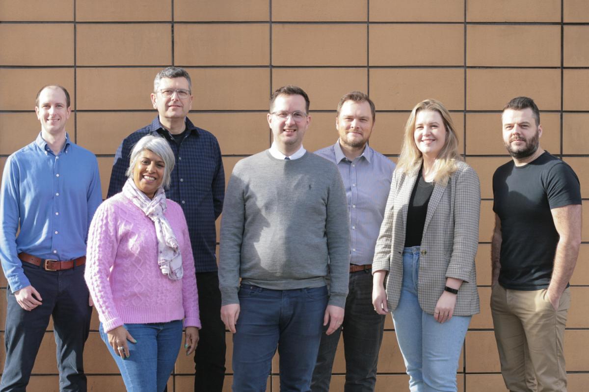 seven people in front of a tiled wall