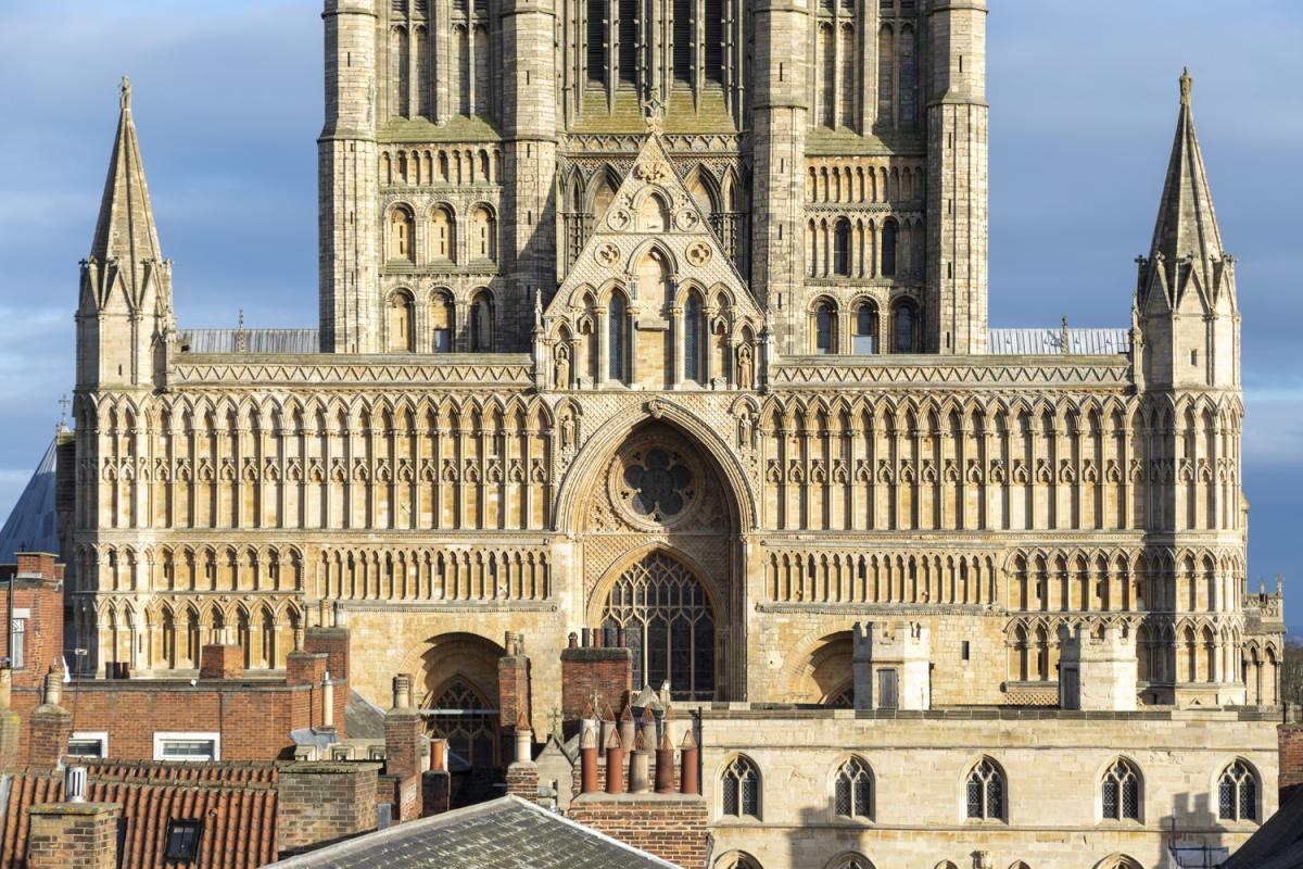 the west front of lincoln cathedral seen above the rooftops