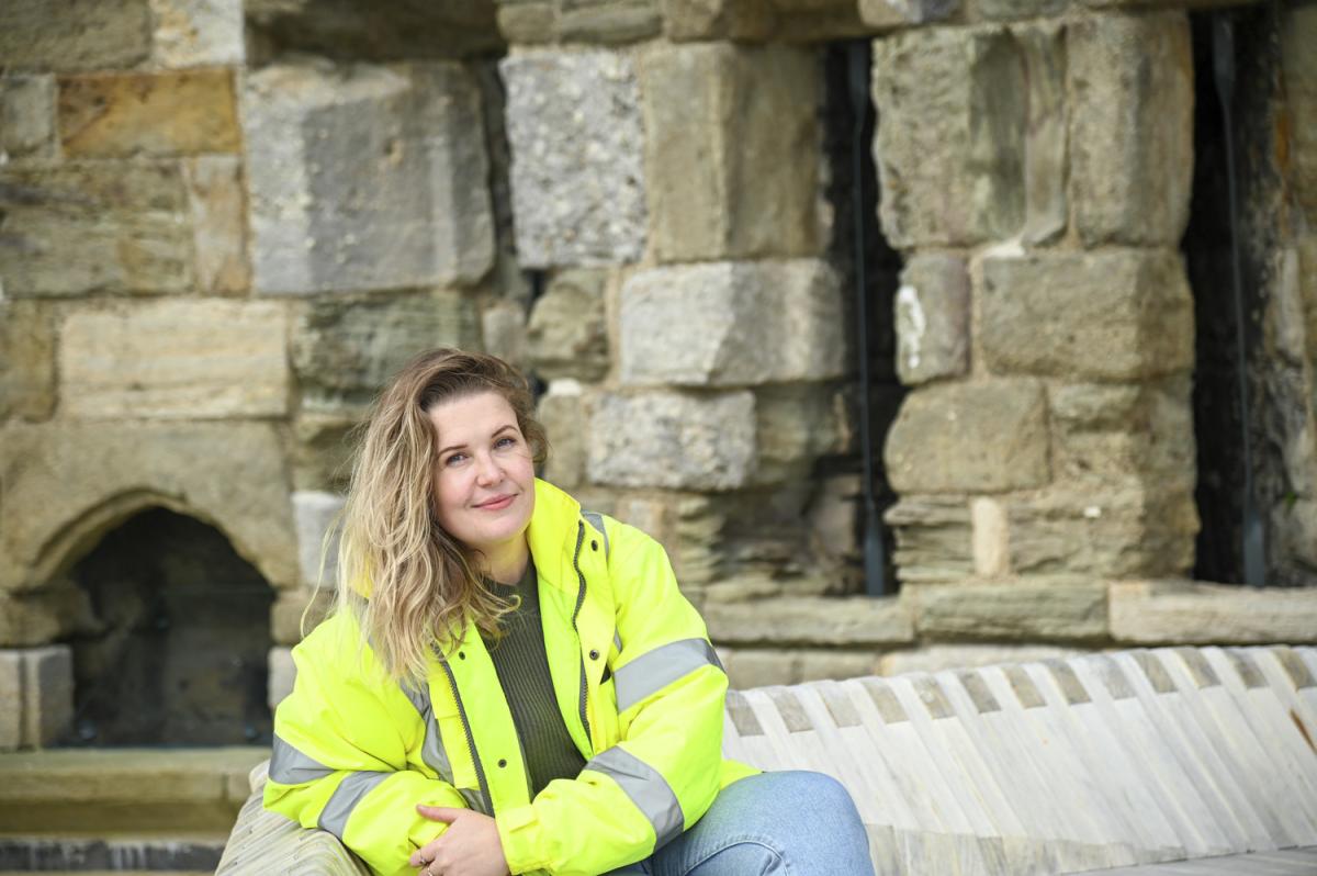 Woman in high visibility jacket sitting on a castle wall