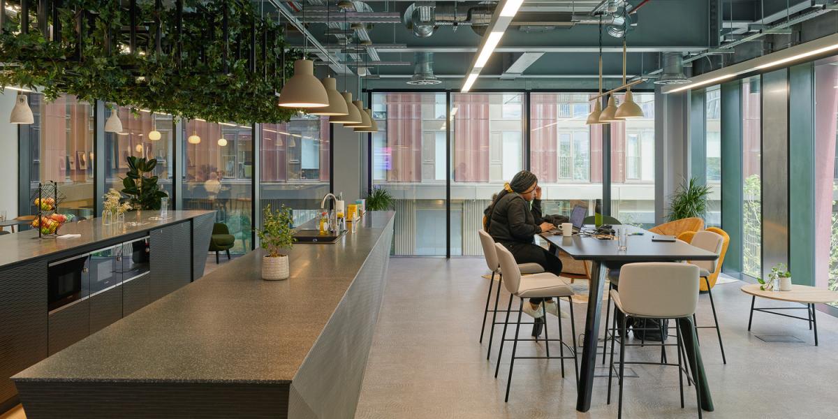 a lady sits and works at a high table in a co-working space