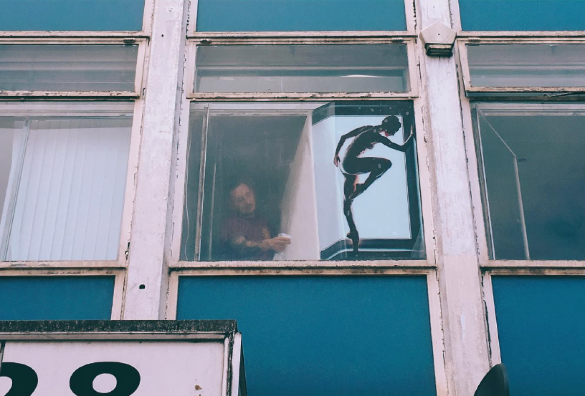 a man puts a vinyl print of a ballerina to the inside of an office window seen from the outside