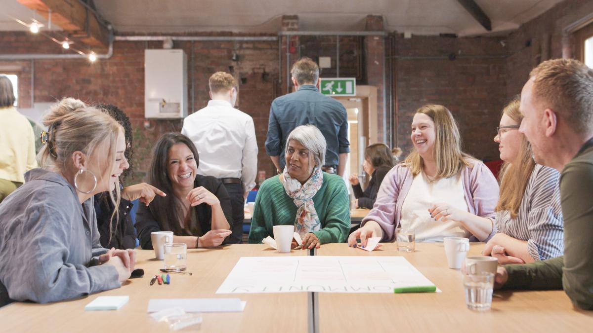 A group of people are sat around a table and laughing