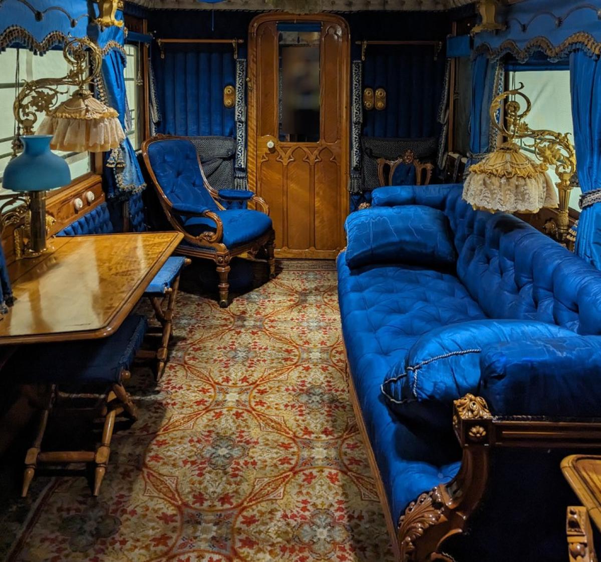 Interior image of Queen Victoria's lounge carriage. The furnishings and decor are a very rich blue. The ceiling is quilted fabric.