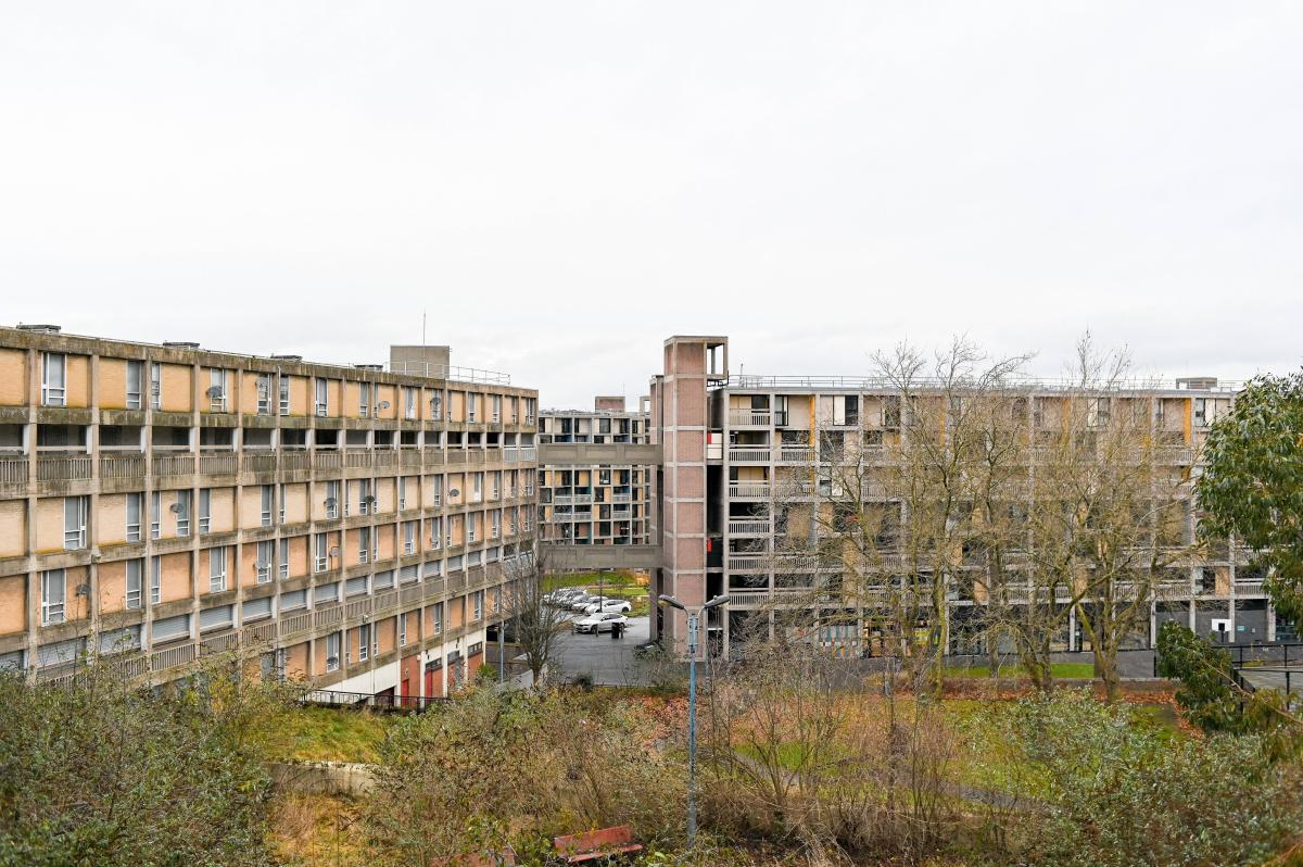 A large, multi-story apartment building with a flat roof and a concrete exterior. Park Hill Flats are a Grade II* listed building in Sheffield, England.