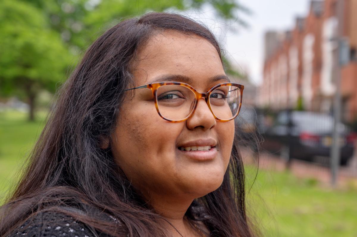 headshot of a lady looking at camera, a park is in the background