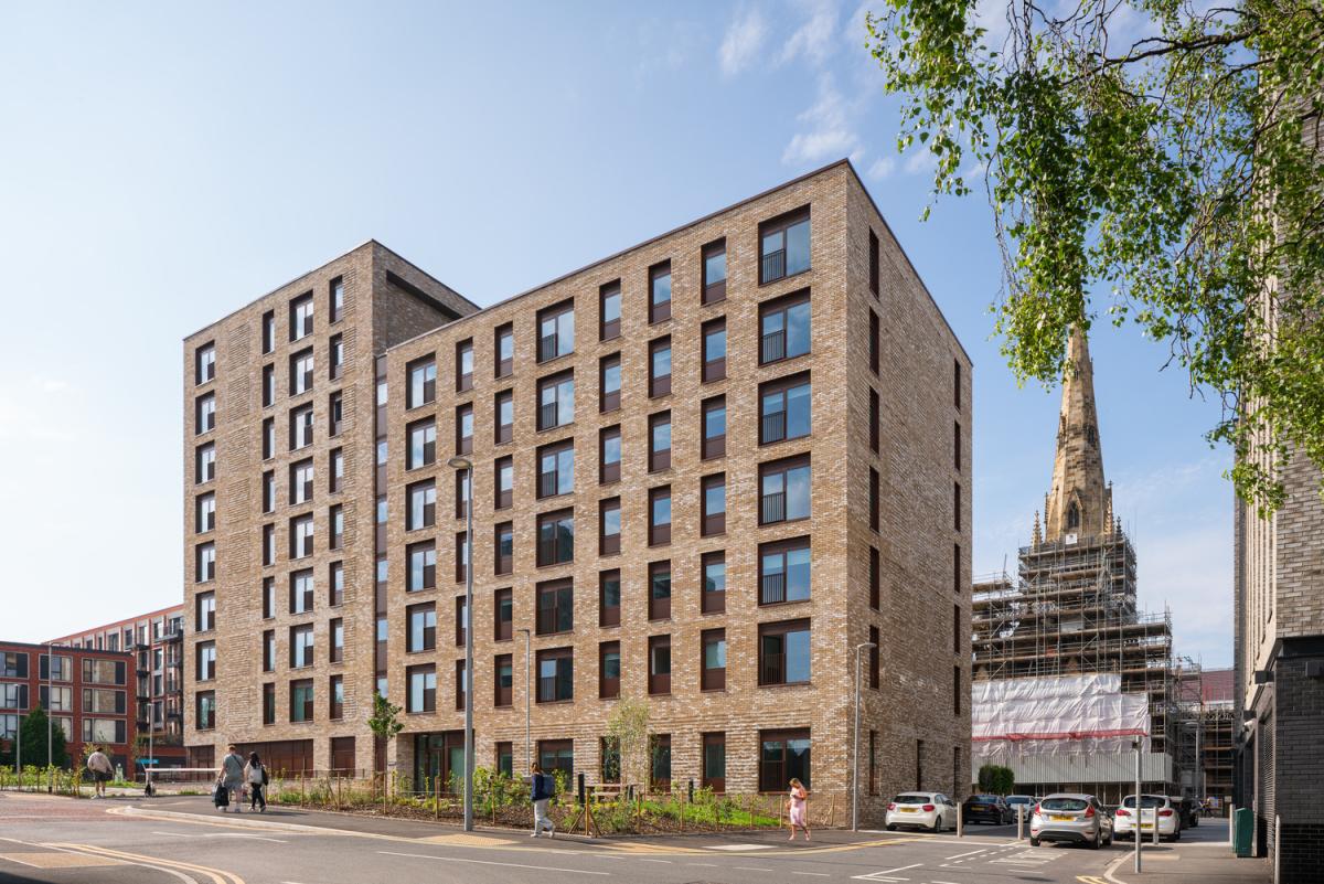 A multi-story building with numerous windows lining its facade, situated along a bustling street.