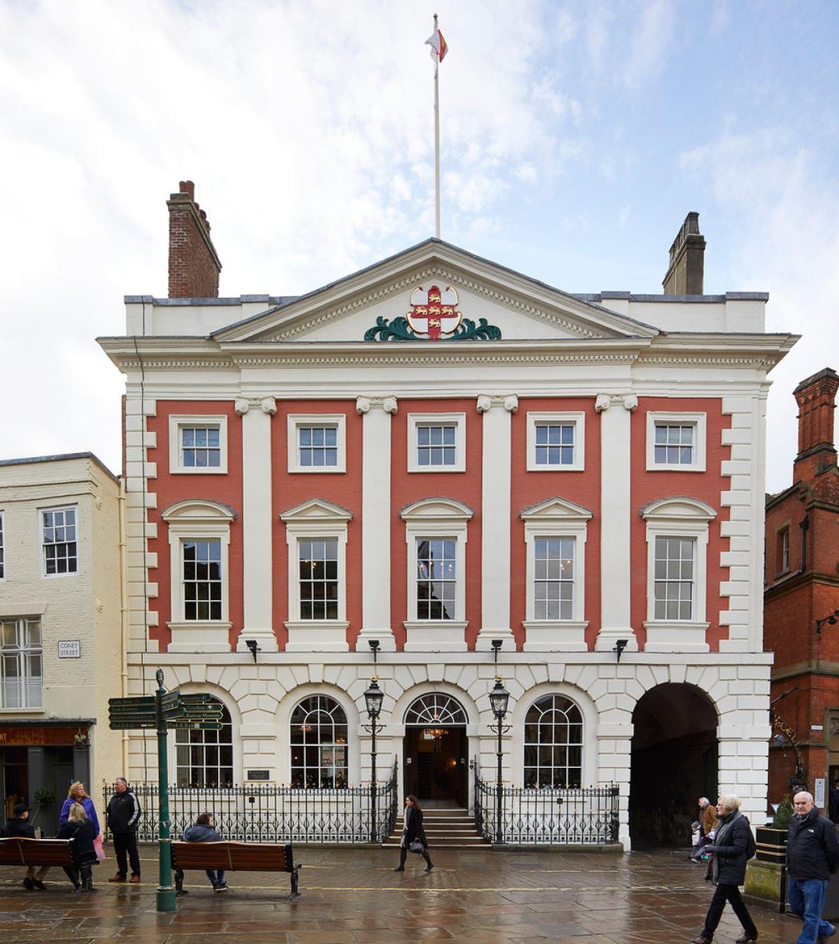 Terracotta building with white columns, windows and bricks - on a bsuy street