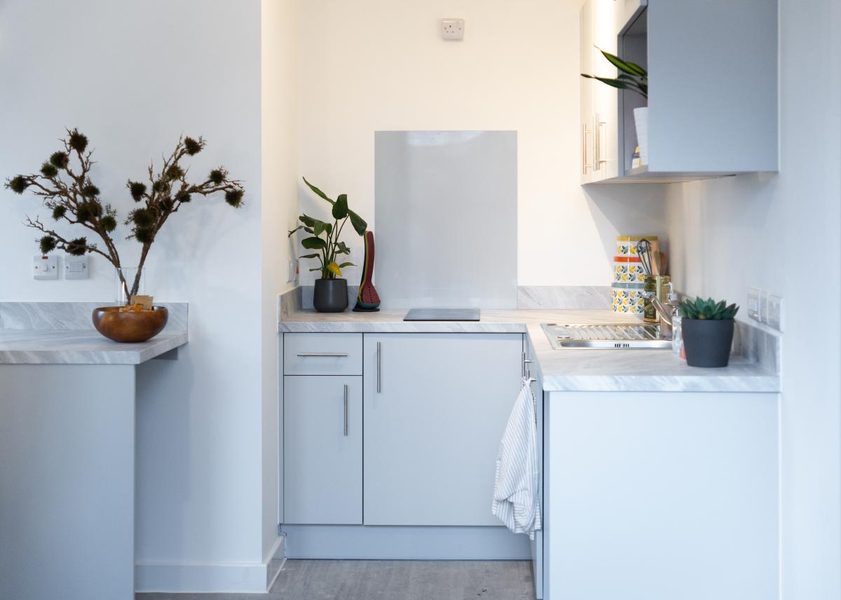 Internal image of a very small kitchen with white cupboards and work surfaces. 