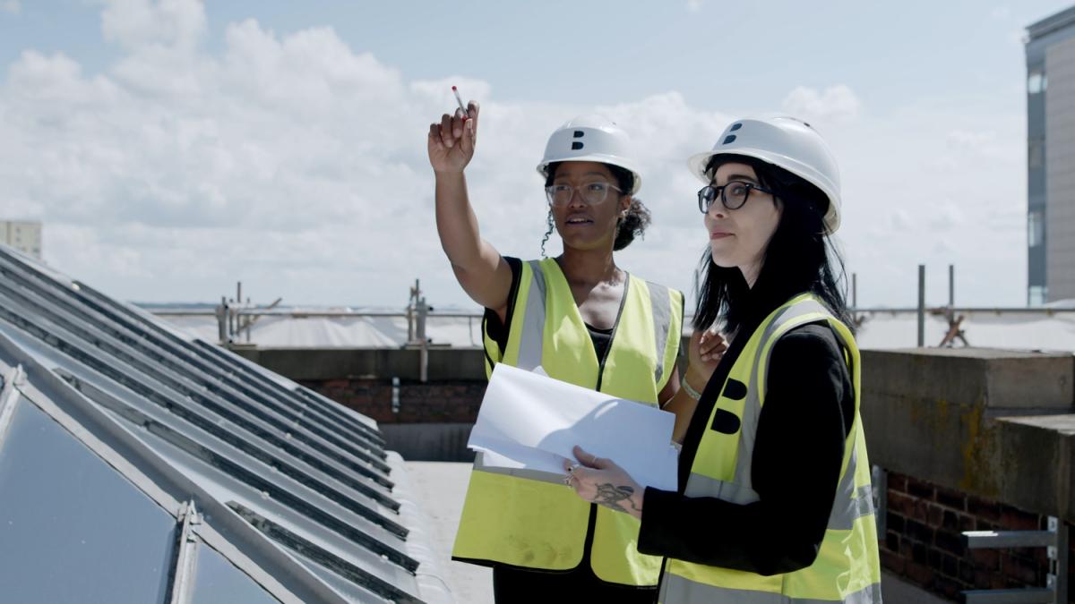 Sam and Lauren - two women on the roof of a museum, wearing high vis vests