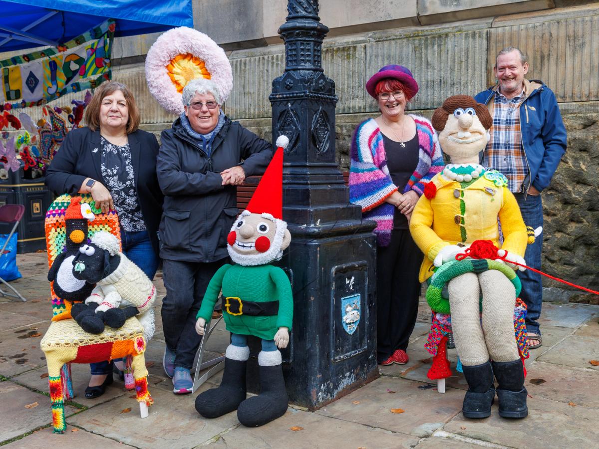A group of people standing behind knitted Wallace and Gromit figures