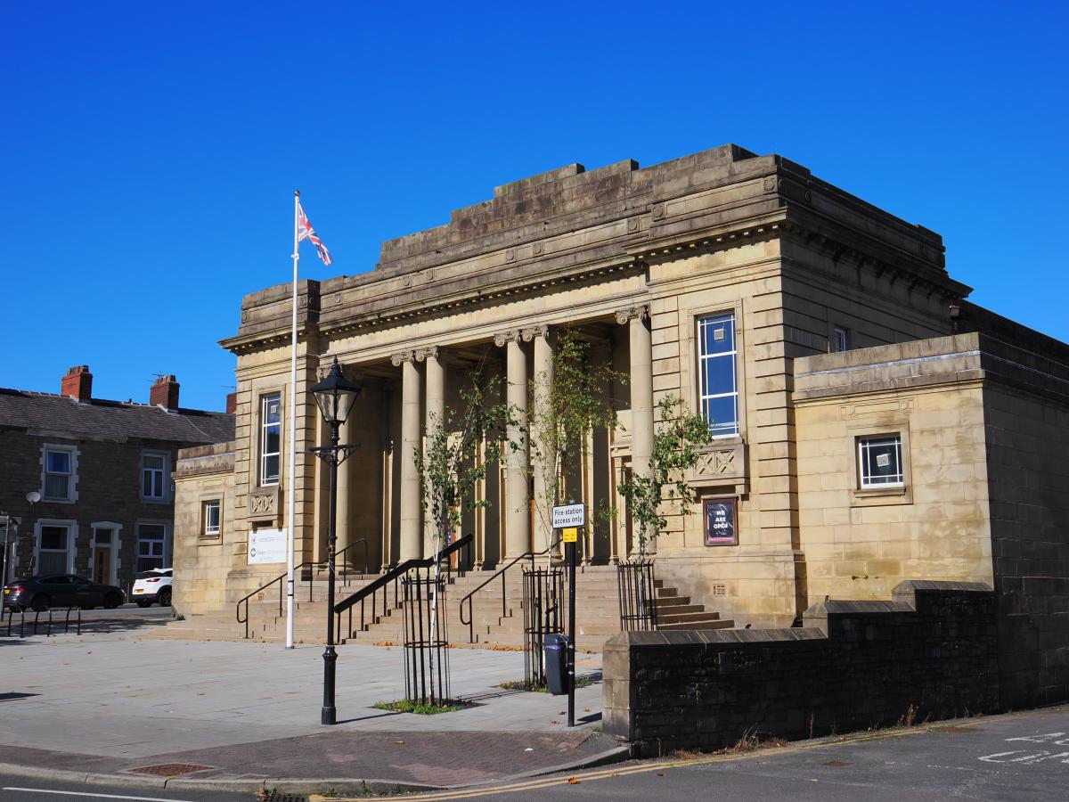 Exterior of Mercer Hall, a historic beige brick building with a blue sky.