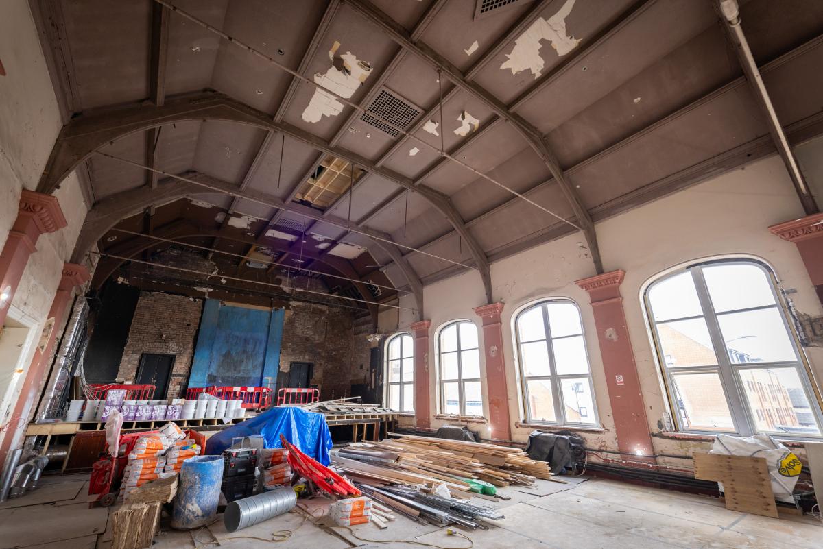 A large event space under restoration with timber and construction tools.