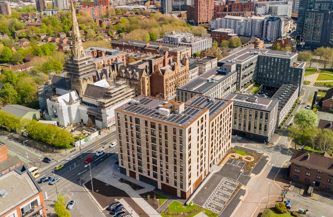an aerial view of apartments made from buff brick salford cathedral is in the background