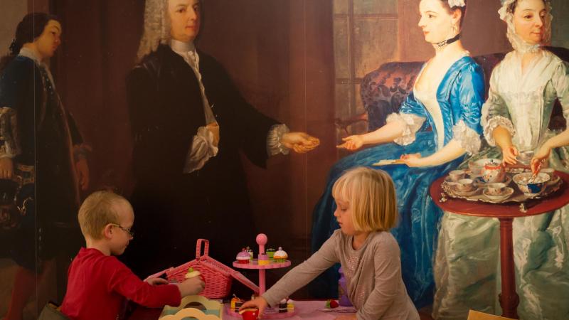 inside the higgins, two children interacting in front of artwork