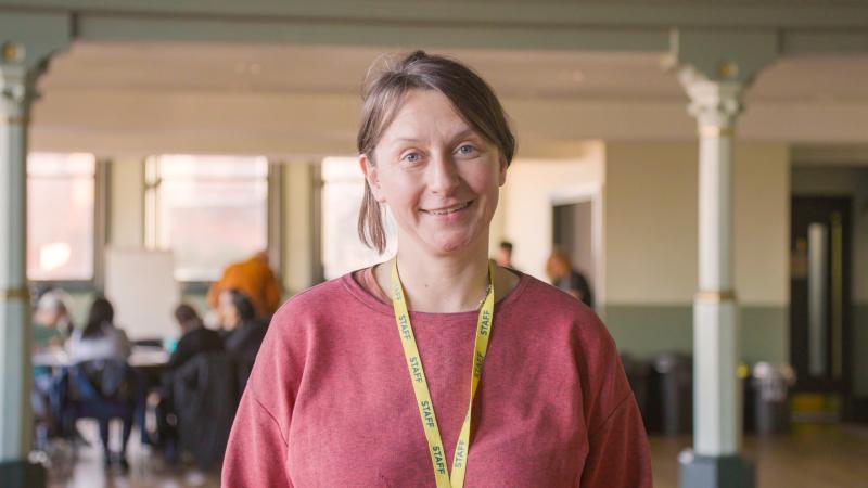 A woman in a pink jumper standing in a historic hall