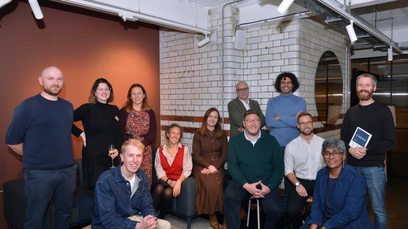 A group of people sitting and standing together looking at the camera.