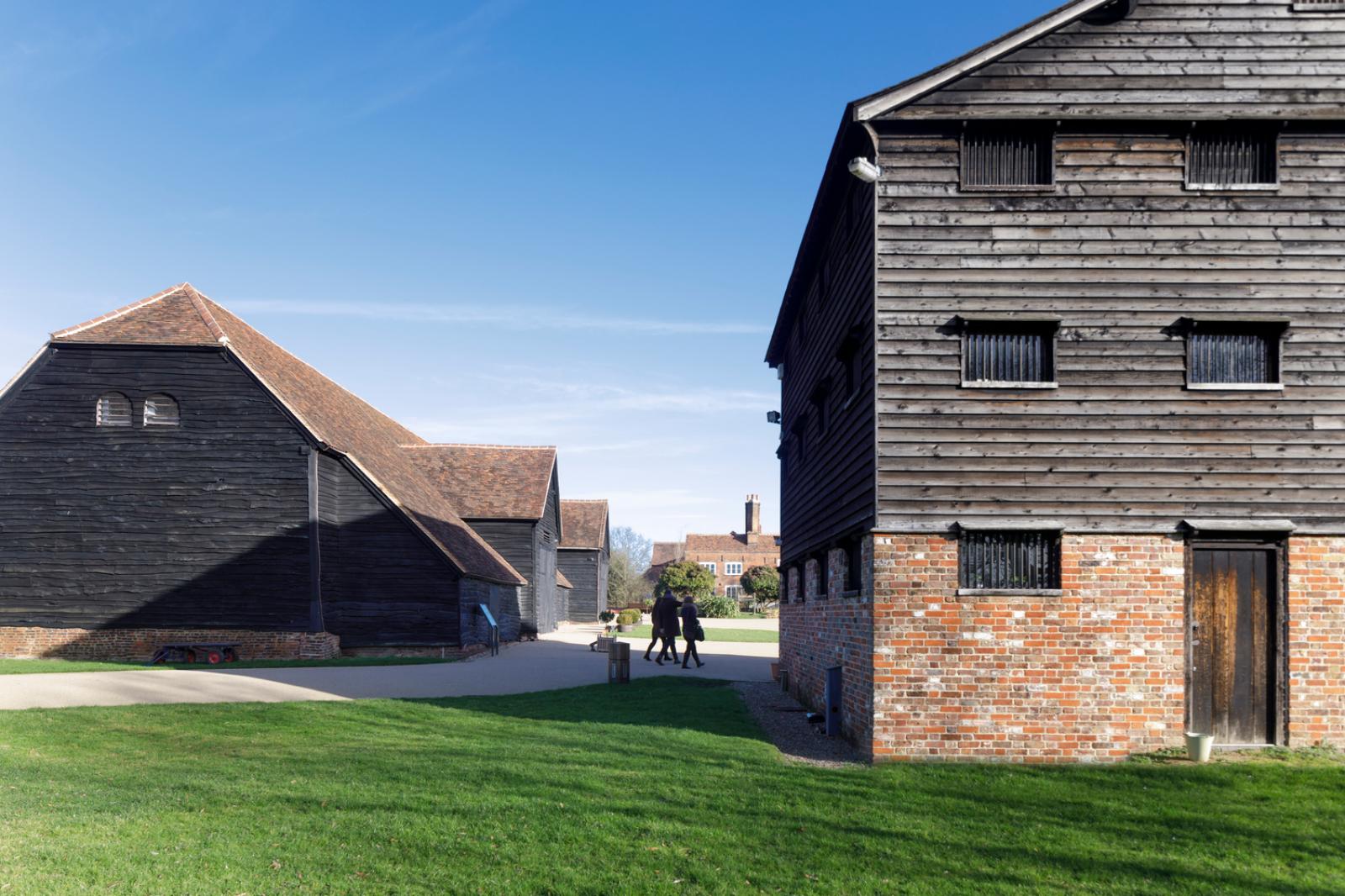 people walk between old barns at headstone manor