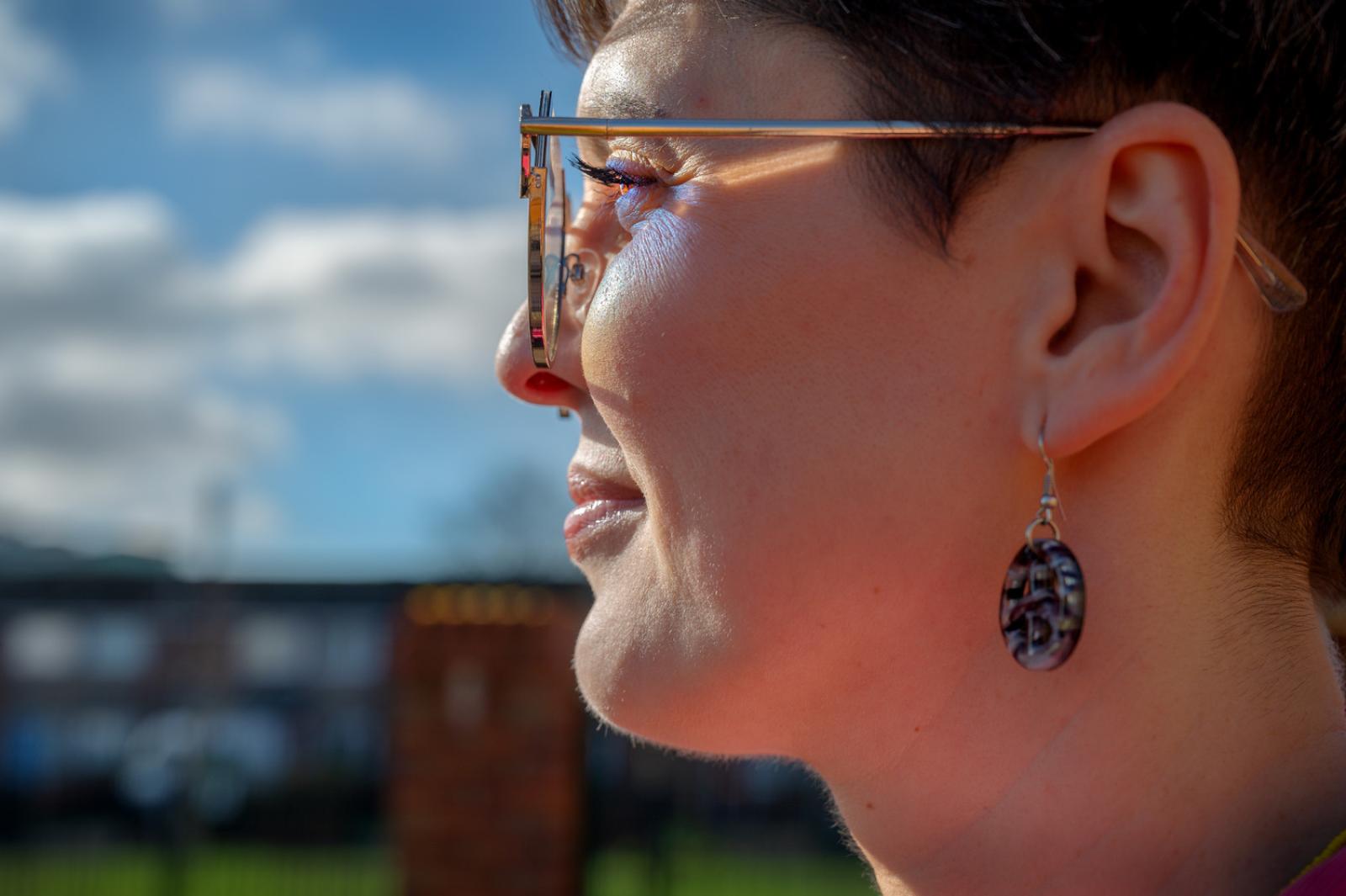 the side profile of a lady with short brown hair wearing sunglasses