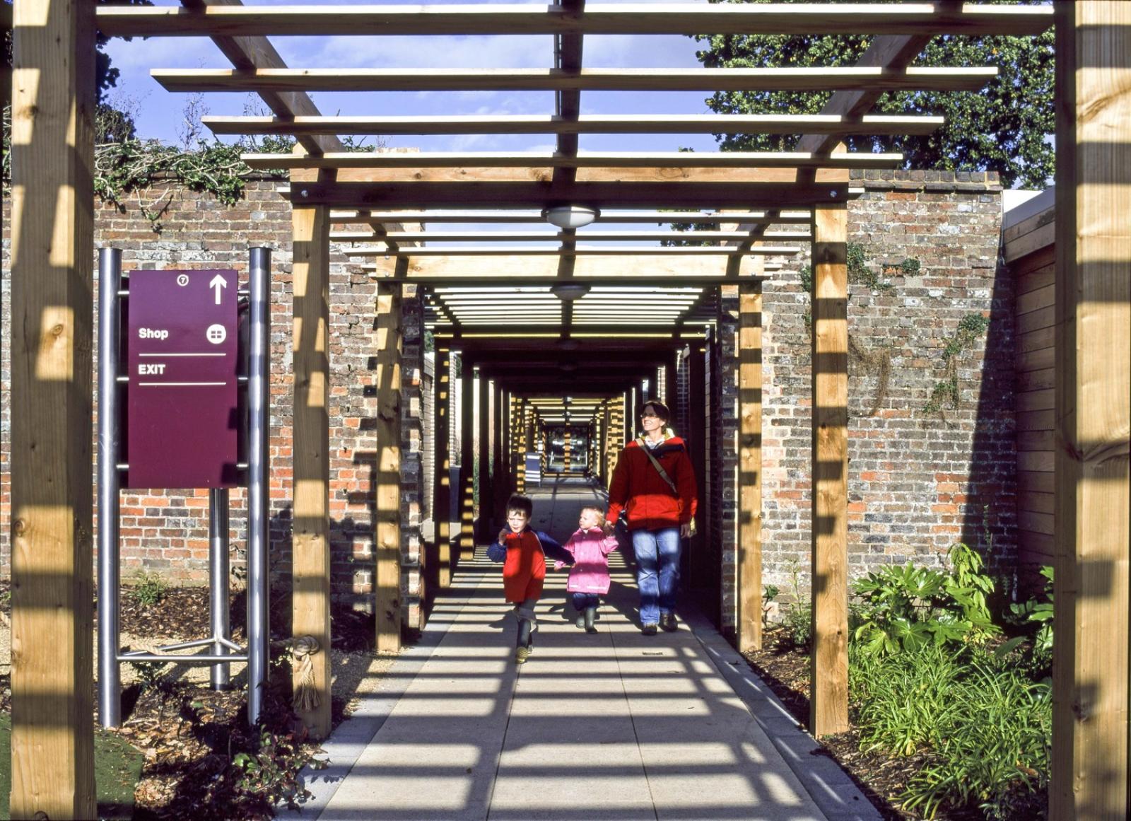 External image of walkway which is framed in wood timbers. The picture takes the viewers eye through the walkway with the timbres framing the picture. People are walking away from the camera.