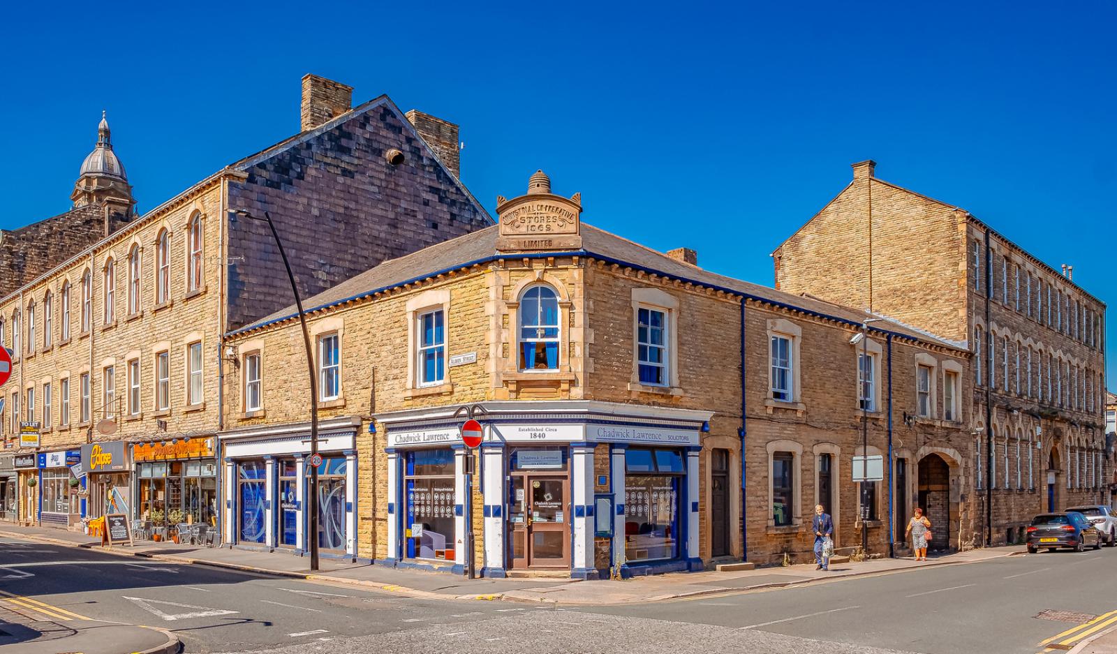 A historic blue and white shopfront in rows of stone buildings on a bright and sunny day.