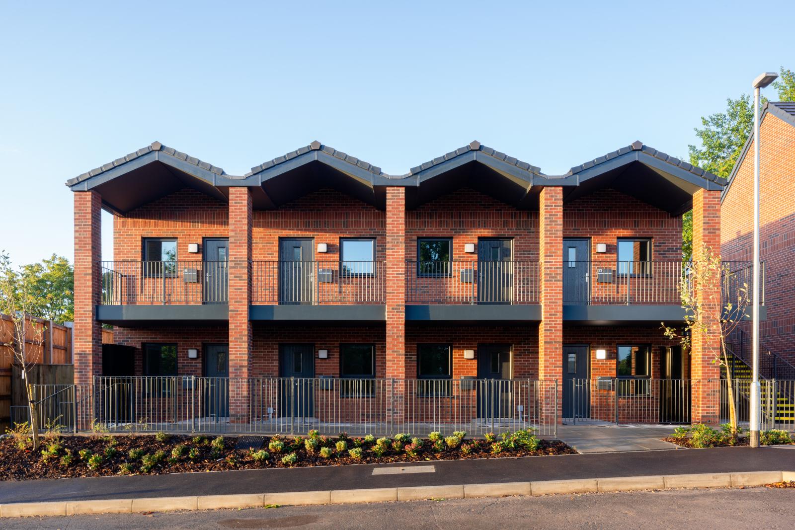 Red brick move on homes, a multi storey building with a grey walkway outside