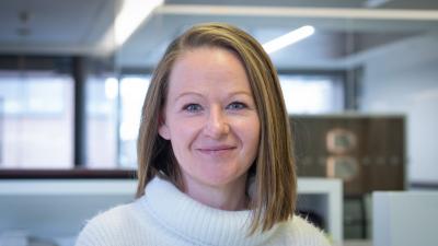 Headshot of Alison Abbott. A woman smiling, wearing a cream jumper.