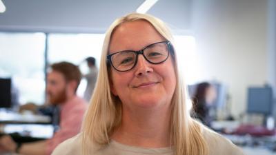 Headshot of Helen Wensley. A woman smiling, wearing glasses and a beige top.