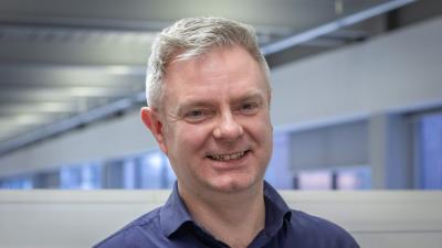 Headshot of Martin Kirkpatrick. A man smiling, wearing a dark blue shirt.