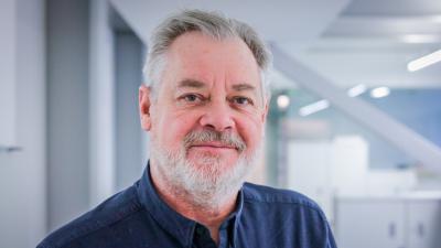 Headshot of Mike Guy. A smiling man wearing a navy blue shirt.
